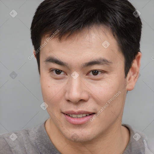 Joyful asian young-adult male with short  brown hair and brown eyes