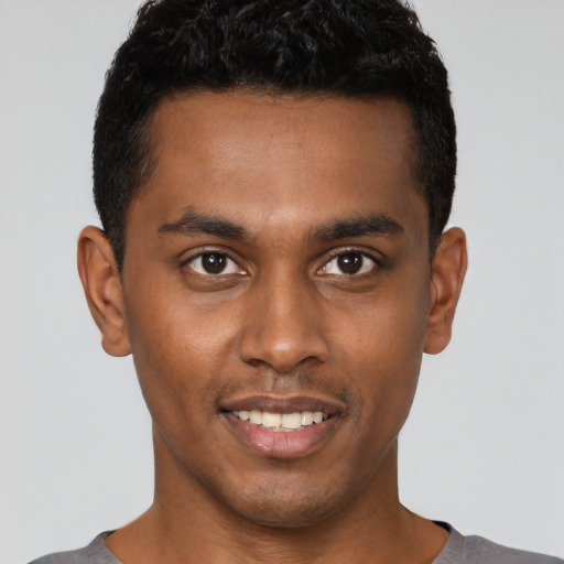 Joyful black young-adult male with short  black hair and brown eyes