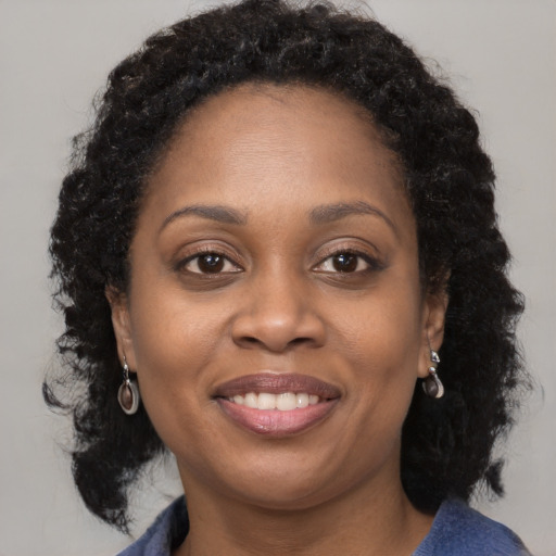 Joyful black adult female with long  brown hair and brown eyes