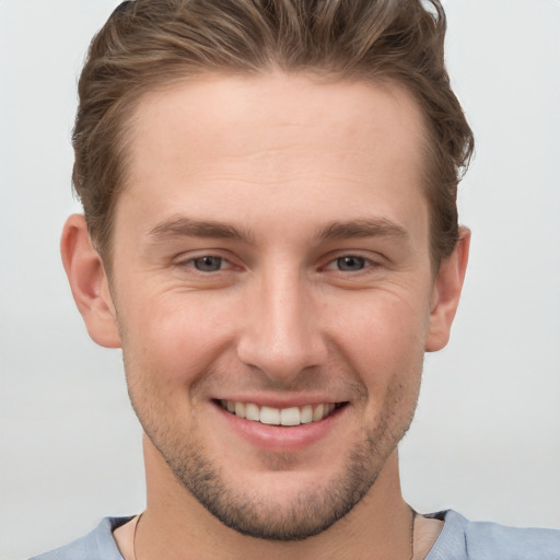 Joyful white young-adult male with short  brown hair and grey eyes