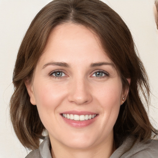 Joyful white young-adult female with medium  brown hair and grey eyes