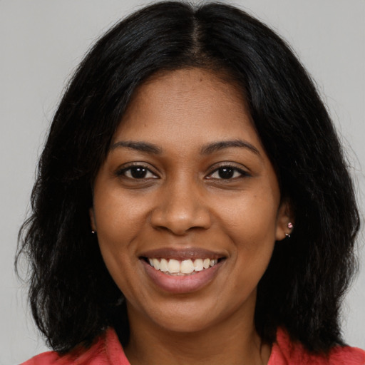 Joyful black young-adult female with long  black hair and brown eyes