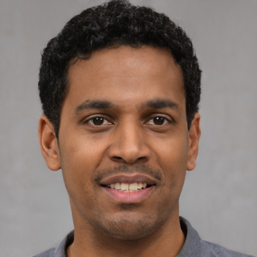 Joyful latino young-adult male with short  black hair and brown eyes
