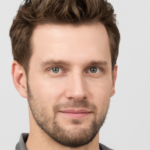 Joyful white young-adult male with short  brown hair and grey eyes