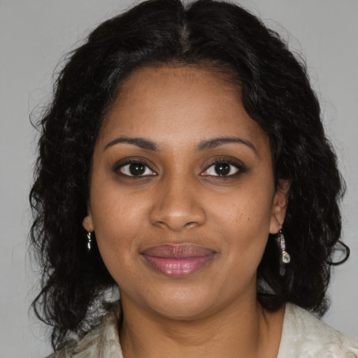 Joyful black young-adult female with long  brown hair and brown eyes
