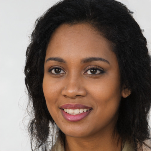 Joyful black young-adult female with long  black hair and brown eyes