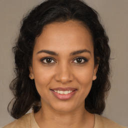 Joyful black young-adult female with long  brown hair and brown eyes