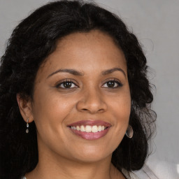 Joyful black young-adult female with long  brown hair and brown eyes