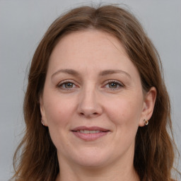 Joyful white adult female with long  brown hair and grey eyes