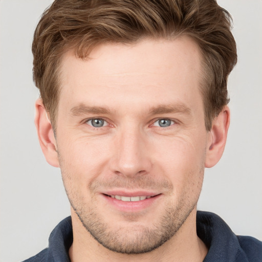 Joyful white young-adult male with short  brown hair and grey eyes