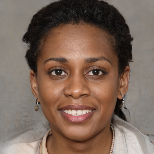 Joyful black young-adult female with short  black hair and brown eyes