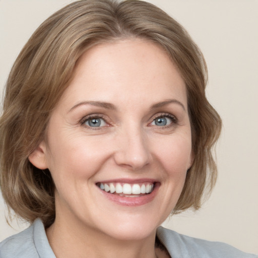 Joyful white adult female with medium  brown hair and blue eyes