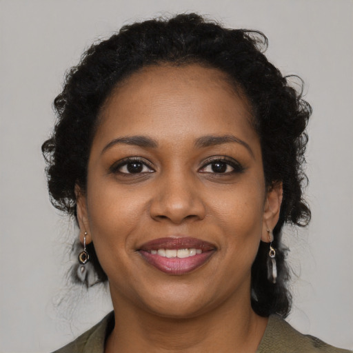 Joyful black young-adult female with long  brown hair and brown eyes
