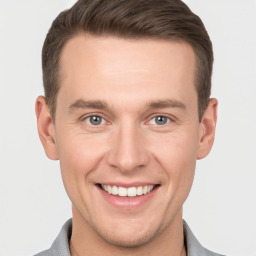 Joyful white young-adult male with short  brown hair and grey eyes