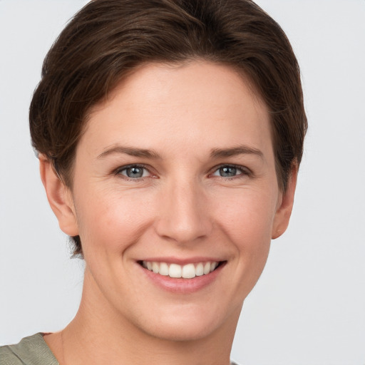 Joyful white young-adult female with short  brown hair and grey eyes