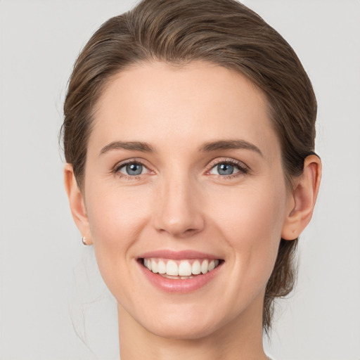 Joyful white young-adult female with medium  brown hair and grey eyes