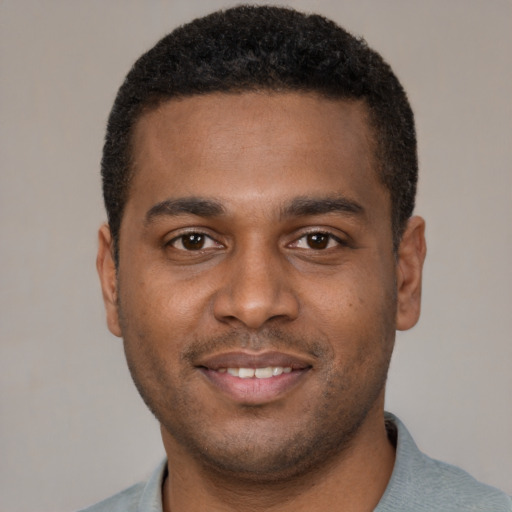 Joyful black young-adult male with short  brown hair and brown eyes