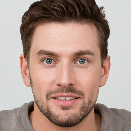 Joyful white young-adult male with short  brown hair and grey eyes