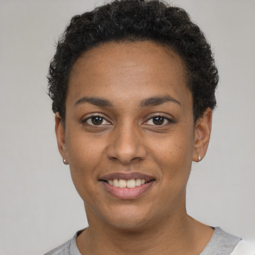 Joyful black young-adult female with short  black hair and brown eyes