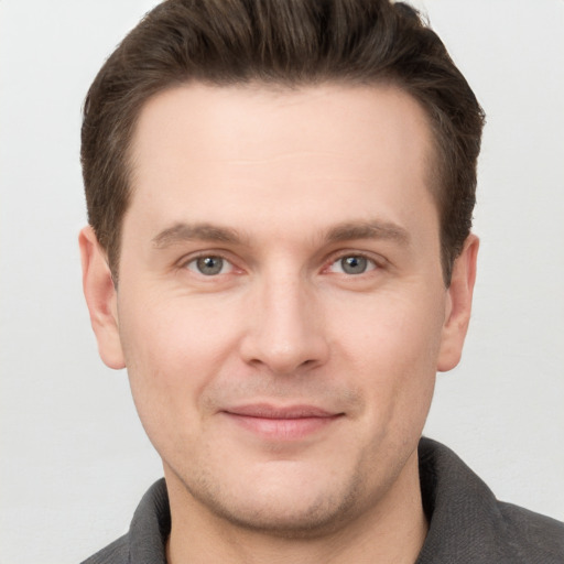 Joyful white young-adult male with short  brown hair and grey eyes