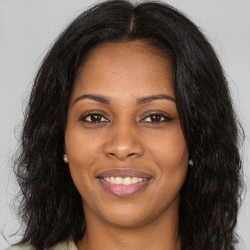 Joyful black young-adult female with long  brown hair and brown eyes