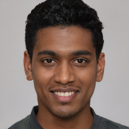 Joyful black young-adult male with short  black hair and brown eyes