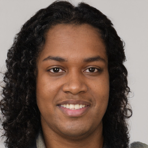 Joyful black young-adult female with long  brown hair and brown eyes