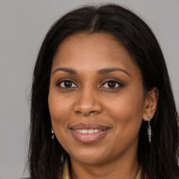 Joyful black young-adult female with long  brown hair and brown eyes