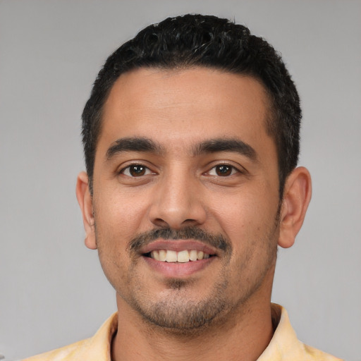 Joyful latino young-adult male with short  black hair and brown eyes