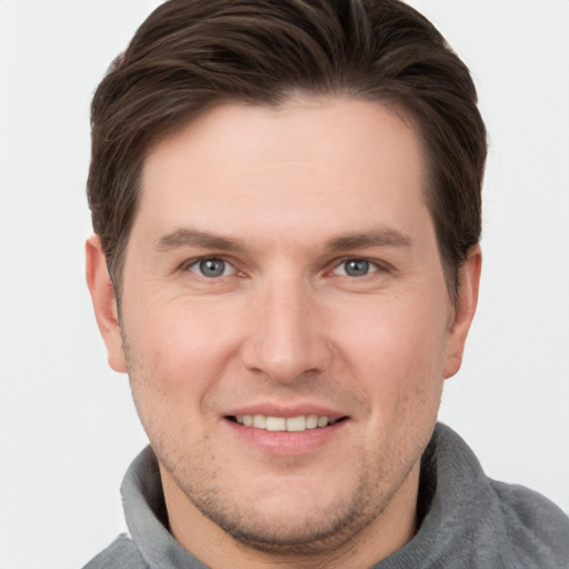 Joyful white young-adult male with short  brown hair and grey eyes