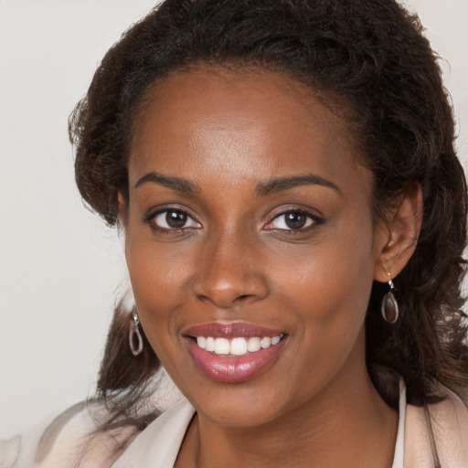 Joyful black young-adult female with long  brown hair and brown eyes