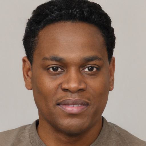 Joyful black young-adult male with short  black hair and brown eyes