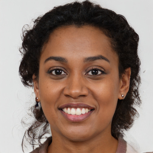 Joyful black young-adult female with long  brown hair and brown eyes