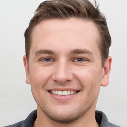 Joyful white young-adult male with short  brown hair and grey eyes