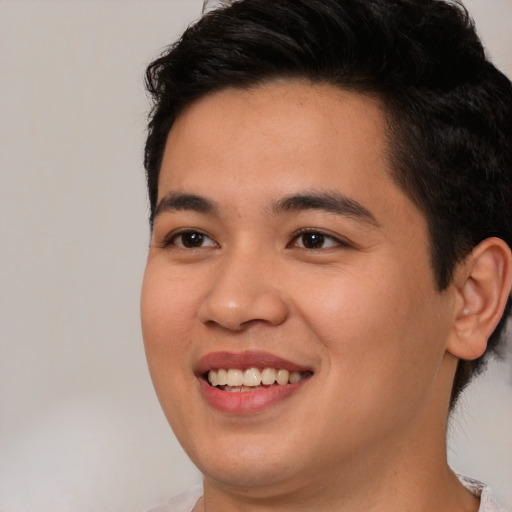 Joyful latino young-adult male with short  brown hair and brown eyes