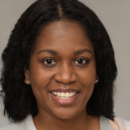 Joyful black young-adult female with medium  black hair and brown eyes