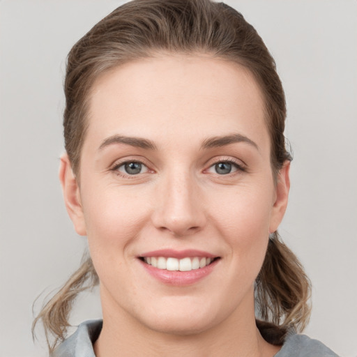 Joyful white young-adult female with medium  brown hair and grey eyes