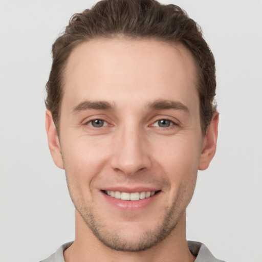 Joyful white young-adult male with short  brown hair and grey eyes