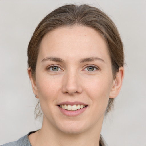 Joyful white young-adult female with medium  brown hair and grey eyes