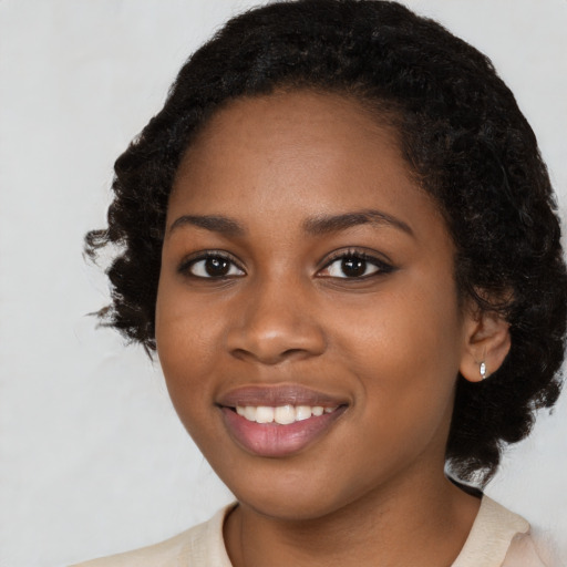 Joyful black young-adult female with long  black hair and brown eyes