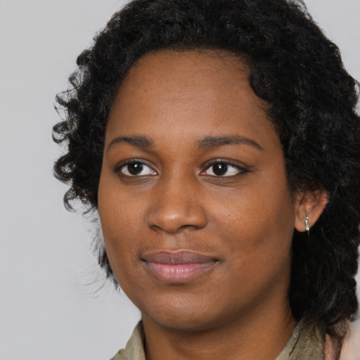 Joyful black young-adult female with long  black hair and brown eyes