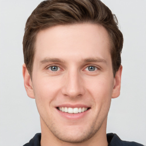 Joyful white young-adult male with short  brown hair and grey eyes