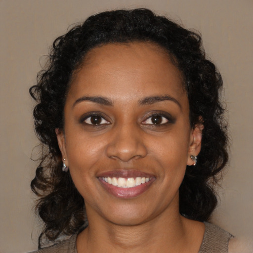 Joyful black young-adult female with long  brown hair and brown eyes