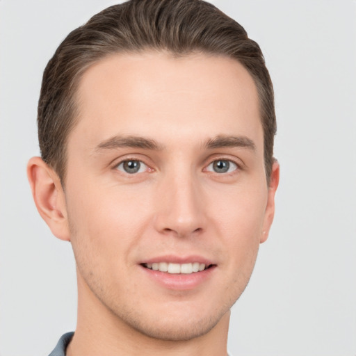 Joyful white young-adult male with short  brown hair and grey eyes