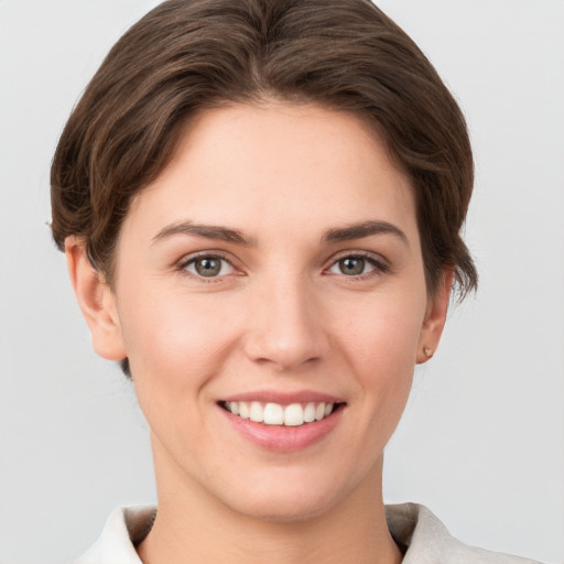 Joyful white young-adult female with short  brown hair and grey eyes