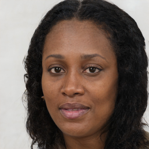 Joyful black young-adult female with long  black hair and brown eyes
