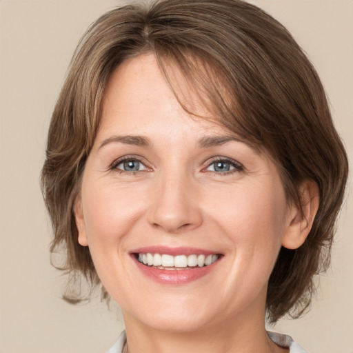 Joyful white young-adult female with medium  brown hair and grey eyes