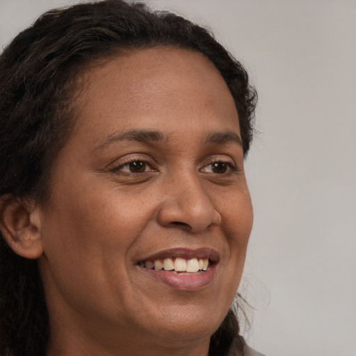 Joyful black adult female with long  brown hair and brown eyes