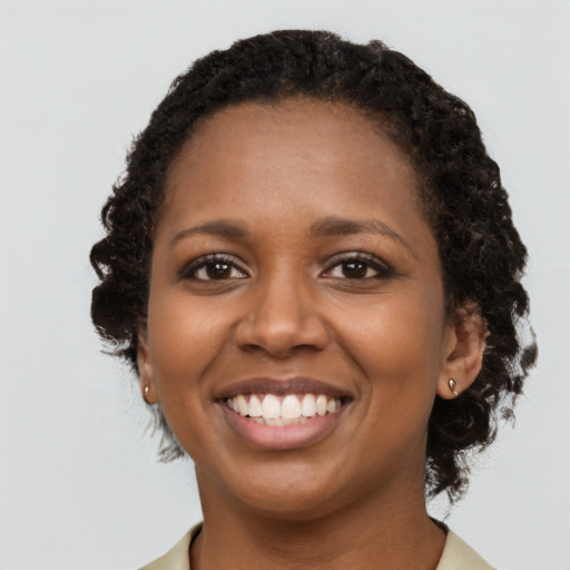 Joyful black young-adult female with long  black hair and brown eyes