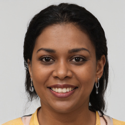 Joyful black young-adult female with long  black hair and brown eyes